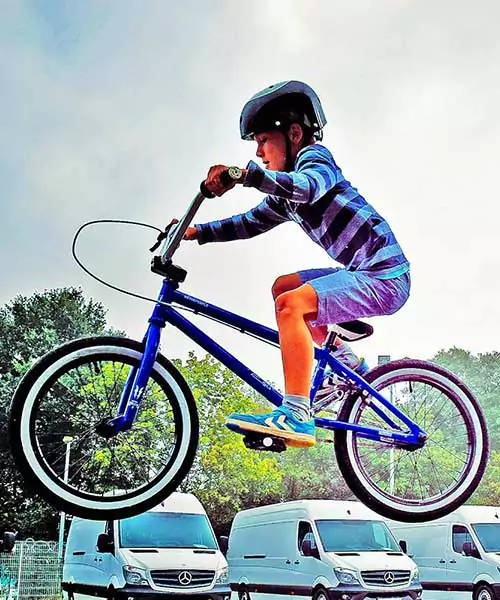 A little boy jumping his bicycle into the air